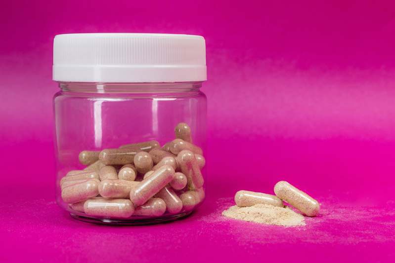 Two women reviewing supplement bottles and wellness notes together at a cozy kitchen table